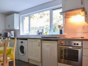 a kitchen with a sink and a washing machine at The Old Smiddy in Poolewe