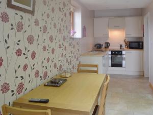 a kitchen with a wooden table with chairs and a kitchen at Valley View - 29530 in Scotforth