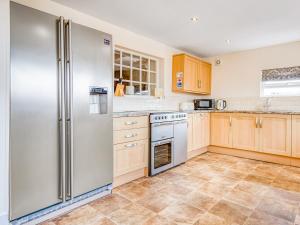 a kitchen with a stainless steel refrigerator and wooden cabinets at The Farmhouse in St Austell +13 photos