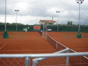 a tennis court with a net and lights on it at Studios Kapsalas in Nea Michaniona