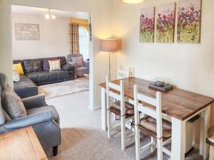 un soggiorno con un tavolo e un divano di 4 Eldin Hall Cottages a Cayton Altre 6 foto