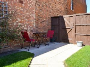 un patio con 3 sillas, una mesa y una valla en The Hideaway, en Sheringham