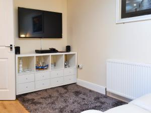 Una sala de estar con un mueble blanco con un televisor en la pared. en The Hideaway, en Sheringham