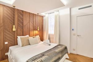 a bedroom with a large white bed with wood paneling at Superb air-conditioned flat on the Champs Elysées in Paris