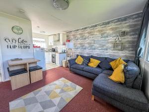 a living room with a blue couch and yellow pillows at Beautiful Chalet With Free Wifi Nearby Hemsby Beach In Norfolk Ref 59096S in Hemsby +13 photos