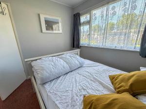 a small bedroom with a bed and a window at Beautiful Chalet With Free Wifi Nearby Hemsby Beach In Norfolk Ref 59096S in Hemsby
