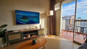 Una sala de estar con un televisor de pantalla plana en la pared. en Boa Localização - Wi-fi - Pitangueiras, en Guarujá