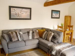 a living room with a gray couch with pillows at Gannet Lodge - Uk30977 in Bempton