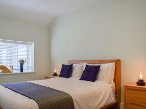 a bedroom with a bed with blue pillows and a window at Brooklands Farm Cottage in Biggleswade