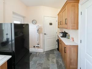 Wellwood Cottage في موربيث: مطبخ مع ثلاجة سوداء ودواليب خشبية
