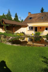 a house with a pond in front of a yard at Villa Isaac - Piscine naturelle - Proche Boulerie Jump - 8p in Le Mans