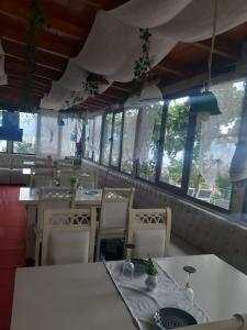 een restaurant met witte tafels, stoelen en ramen bij Stone dream in Polje