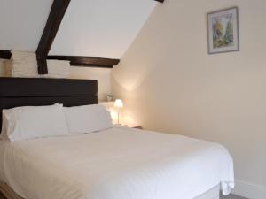 ein Schlafzimmer mit einem weißen Bett mit einem schwarzen Kopfteil in der Unterkunft Paddock Cottage - Ukc3783 in West Down