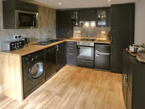 a kitchen with black cabinets and a washer and dryer at The Old Explorers in Pateley Bridge