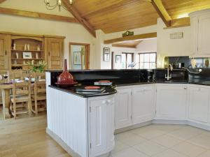 a kitchen with white cabinets and a black counter top at Ty Cerrig Farmhouse in Banc-y-felin