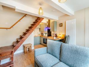 a living room with a blue couch and a kitchen at Duckling Cottage in Addingham