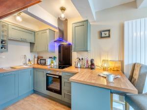 a kitchen with blue cabinets and a counter at Duckling Cottage in Addingham