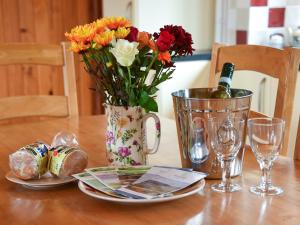 a table with a vase of flowers and a bottle of wine at Ash Lodge - Hw7442 in Nantmel