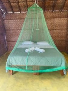 a bed in a room with a green net at Hampi Firangi Cafe in Hampi