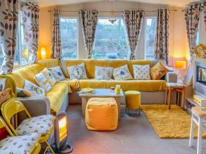 a living room with a yellow couch and a tv at The Hive in Hawick