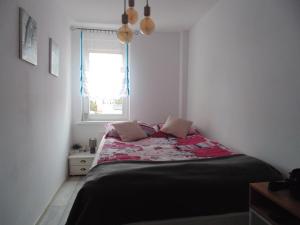 a small bedroom with a bed with a window at Apart Bella in Uniejow