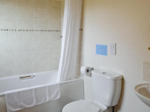 a bathroom with a toilet and a shower and a sink at Kingfisher Cottage - 25114 in Flamborough +5 photos