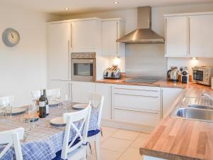 eine Küche mit weißen Schränken und einem Tisch mit Stühlen in der Unterkunft Good Tides in Beadnell + 14 Fotos
