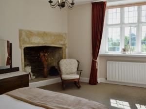 1 dormitorio con silla y chimenea en The Farmhouse, en Holwell