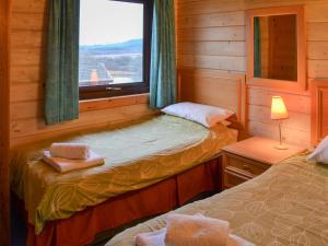 ein kleines Zimmer mit zwei Betten und einem Fenster in der Unterkunft Lodge 59 in Woolfardisworthy