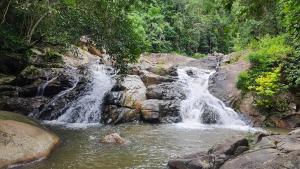 a waterfall in the middle of a river at Backpack Bay in Amphoe Koh Samui +6 photos