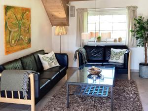 a living room with a black leather couch and a table at 5 star holiday home in Væggerløse in Bøtø By