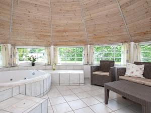 a large bathroom with a tub and chairs and windows at 12 person holiday home in Væggerløse in Marielyst