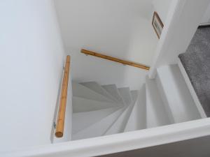 a white staircase with a wooden rail on it at Sea Thistle Cottage in Nairn