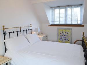 a bedroom with a white bed and a window at Sea Thistle Cottage in Nairn