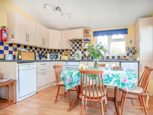 eine Küche mit einem Tisch mit Stühlen und einer Tischdecke darauf in der Unterkunft Skylarks in Saint Merryn