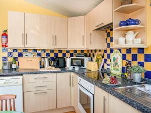 eine Küche mit weißen Schränken und blauen Fliesen in der Unterkunft Skylarks in Saint Merryn