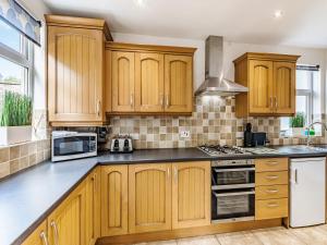a kitchen with wooden cabinets and a stove top oven at Heughendon in Rothbury