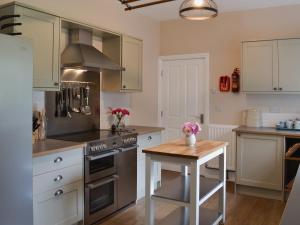 a kitchen with stainless steel appliances and a wooden table at The Garden Cottage in Rudston
