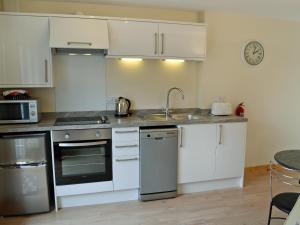 a kitchen with white cabinets and a sink at The Honeypot in Padstow