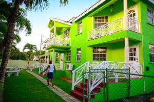 a woman walking in front of a green building at Best E Villas Prospect St James in Saint James