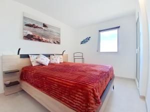 a bedroom with a bed with a red blanket and a window at Appartement lumineux avec vue mer magnifique dans le Domaine du Grand Duc in Mandelieu-la-Napoule