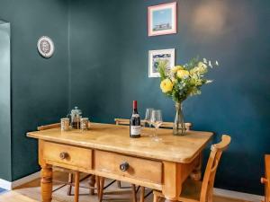 a table with a bottle of wine and a vase of flowers at Mcenroe Cottage in Broadstairs