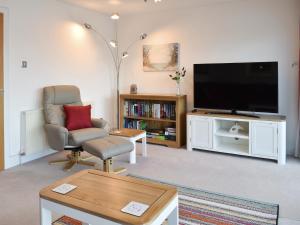 Una sala de estar con un televisor de pantalla plana y una silla. en Kings Haven, en Turnchapel