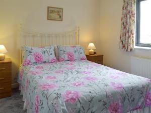 una camera da letto con un letto con fiori rosa di Carol's Cottage - E3043 a Blyford