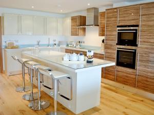 una cocina con una gran isla blanca con taburetes de bar en Gylly Beach View - Tor, en Falmouth