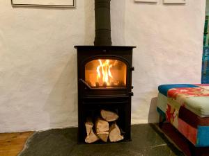 a stove with a fire in a room at Chapel Barn in Bodmin