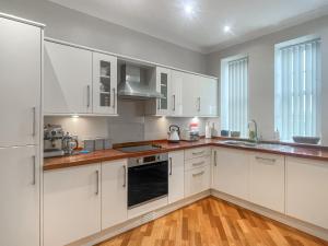 a white kitchen with white cabinets and wooden floors at The Court House - Uk43908 in Silloth