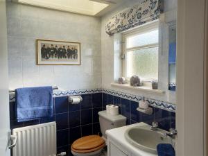 a blue tiled bathroom with a toilet and a sink at Tarandoun Cottage in Helensburgh