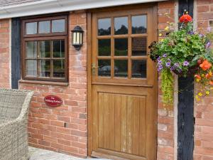 a brick building with a wooden door and flowers at The Milking Parlour in Sidbury