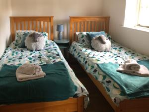 zwei Betten mit ausgestopften Tieren in einem Schlafzimmer in der Unterkunft Princess Cottage in Martin